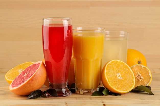 Zitrussäfte. Orangen-, Zitronen- und Grapefruitsaft mit frischen Früchten auf natürlichem Holzhintergrund.