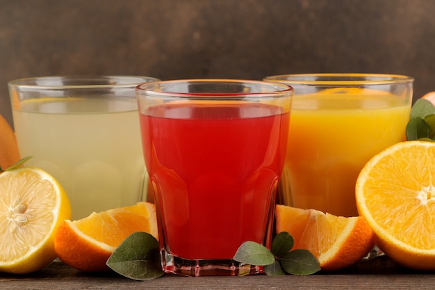 Zitrussäfte. Zitronen-, Grapefruit- und Orangensaft mit frischen Früchten auf einem braunen Holztisch