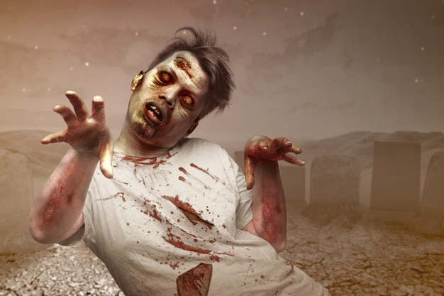Zombie aterrador con sangre y herida en su cuerpo caminando en el cementerio
