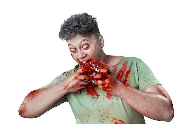 Zombie aterrador con sangre y herida en su cuerpo come la carne cruda aislada sobre fondo blanco