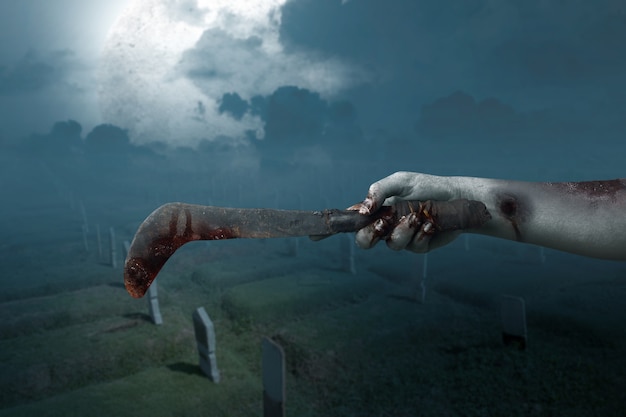 Zombiehände mit Wunde, die Sichel mit dem Nachtszenenhintergrund hält