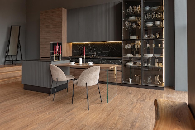 Zona de cocina en un elegante y caro interior de una casa de lujo con un diseño moderno en negro y marrón oscuro con molduras de madera y luz led