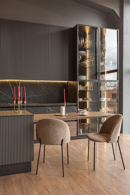 Zona de cocina en un elegante y caro interior de una casa de lujo con un diseño moderno en negro y marrón oscuro con molduras de madera y luz led