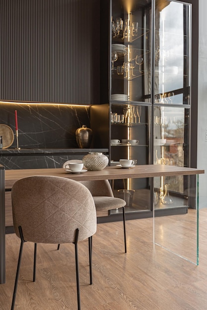 Zona de cocina en un elegante y caro interior de una casa de lujo con un diseño moderno en negro y marrón oscuro con molduras de madera y luz led