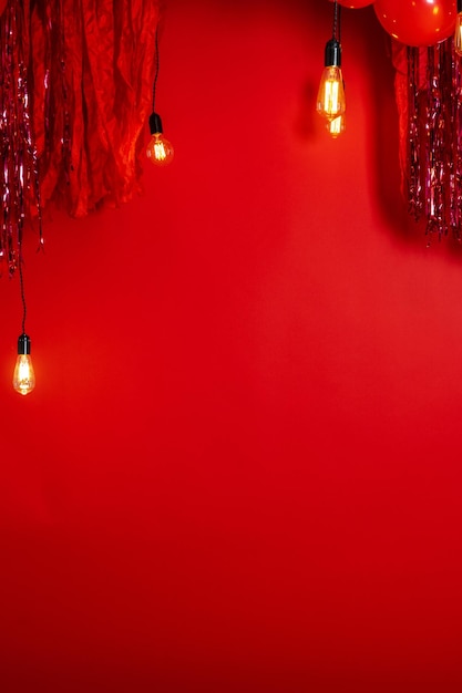 Zona de fotos con papel tapiz rojo, globos rojos y luces.