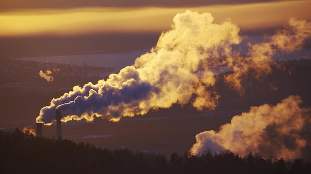 Zona industrial con una gran tubería roja y blanca se vierte humo blanco espeso de la tubería de fábrica en contraste con el sol