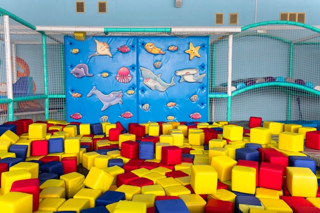 Zona de juegos con bloques de colores suaves y un muro de escalada azul