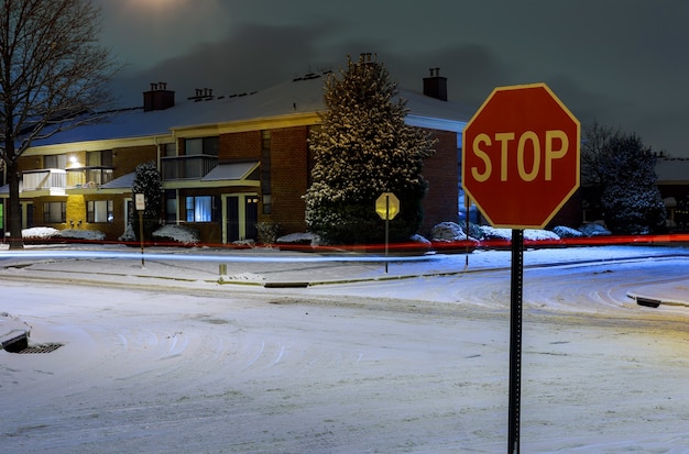 Zona residencial de invierno en la calle por la noche con coches aparcados cubiertos de nieve