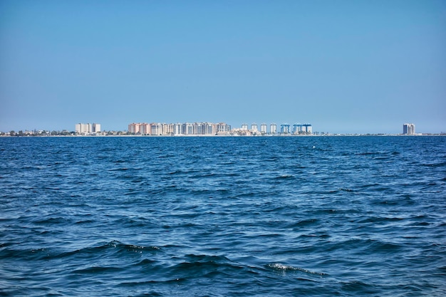 Zona turística de apartamentos en La Manga del Mar Menor visto desde el interior dicho mar en un día de cielo azul claro