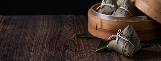 Zongzi. Bola de masa de arroz para el Festival del Barco del Dragón tradicional chino (Festival Duanwu) sobre fondo de mesa de madera oscura.