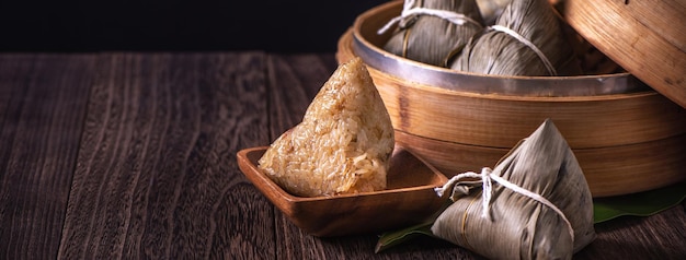 Zongzi bolinho de arroz chinês zongzi em um navio a vapor na mesa de madeira fundo preto retrô para a celebração do Dragon Boat Festival fechar espaço de cópia