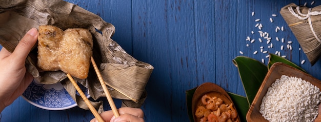 Zongzi-Reisknödel mit Draufsicht der Zutaten für das chinesische traditionelle Drachenboot-Festival (Duanwu-Festival) über blauem Holztischhintergrund