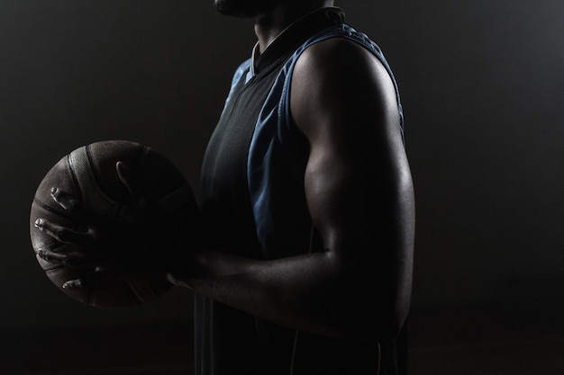 Zoom en un lado de un jugador de baloncesto sosteniendo una pelota de baloncesto