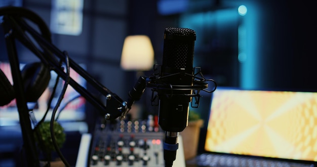 Zoom en un micrófono profesional en un estudio con poca luz utilizado para grabar audio durante un programa de Internet