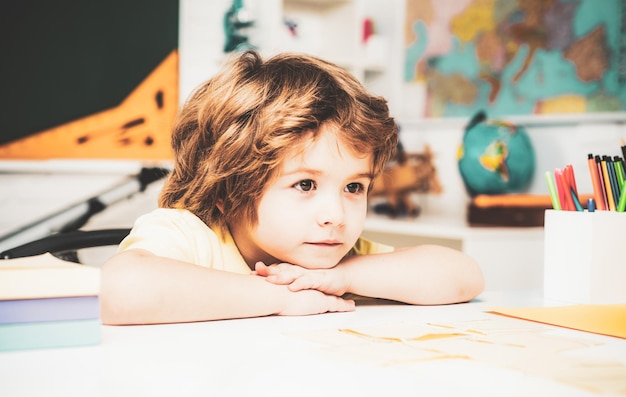 Foto zu beginn des unterrichts bereiten sich die kinder auf die schule vor. ein fröhliches, süßes, fleißiges kind sitzt an einem schreibtisch