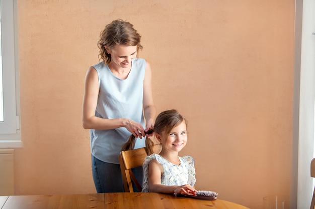 Zu Hause bürstet Mama ihrer Tochter die Haare.