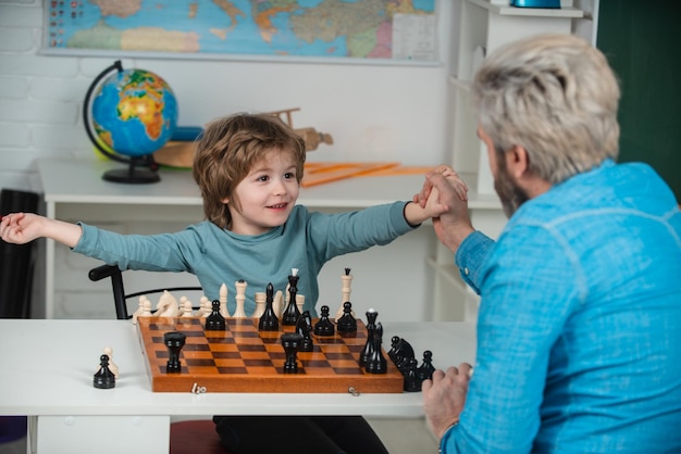 Zu Hause spielt Papa mit seinem kleinen Sohn Schach Schachstrategie Zurück zum Schul- und Bildungskonzept