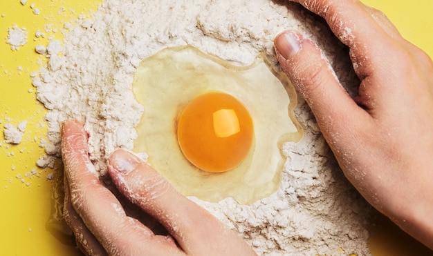 Zubereitung des Teigs mit den Händen Ei in Mehl Zutaten zum Kochen zum Backen Kneten von Teig für Gebäck