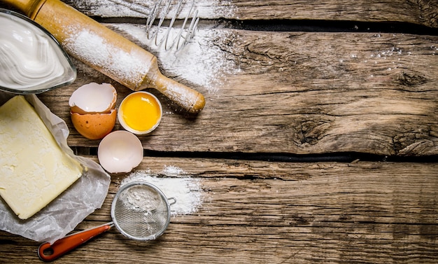 Zubereitung des Teigs. Zutaten für den Teig - Ei, Mehl, Butter mit einem Nudelholz. Auf einem Holztisch. Freier Platz für Text. Draufsicht