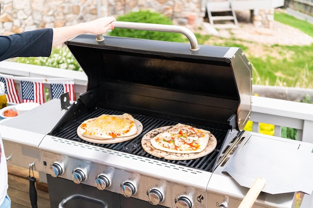 Zubereitung individueller Grillpizzen auf einem Outdoor-Gasgrill.