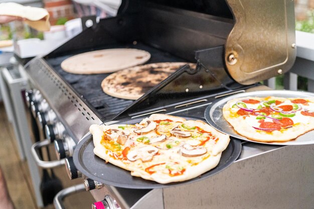 Zubereitung individueller Grillpizzen auf einem Outdoor-Gasgrill.