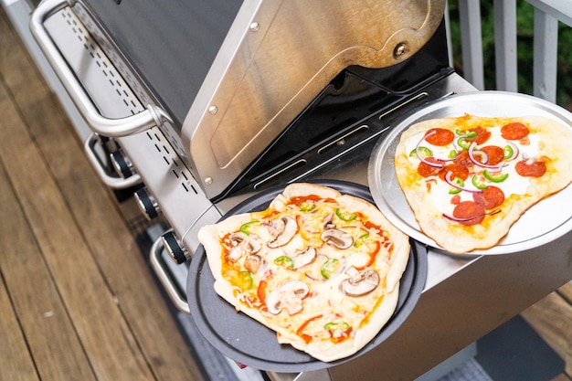 Zubereitung individueller Grillpizzen auf einem Outdoor-Gasgrill.