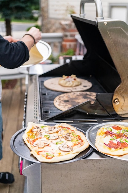 Zubereitung individueller Grillpizzen auf einem Outdoor-Gasgrill.