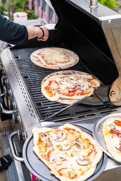 Zubereitung individueller Grillpizzen auf einem Outdoor-Gasgrill.