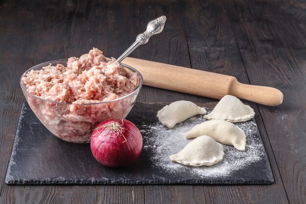 Zubereitung, Kochen, hausgemachte Ravioli, Pelmeni oder Knödel mit Fleisch auf Holztisch Draufsicht