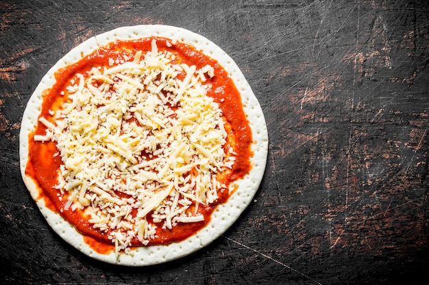 Zubereitung Pizza: Ausgerollter runder Teig mit Tomatenmark und Käse