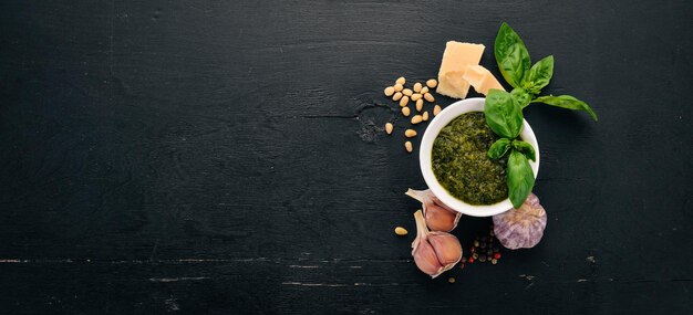 Zubereitung von Basilikum-Pesto-Sauce Basilikum-Parmesan-Käse-Olivenöl Draufsicht auf schwarzem Holzhintergrund Freier Platz für Text