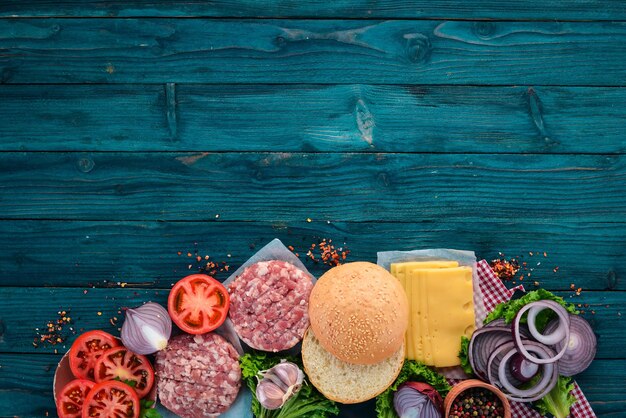 Zubereitung von Burger Fleisch Tomaten Zwiebeln Auf einem blauen Hintergrund aus Holz Draufsicht Freier Kopierraum