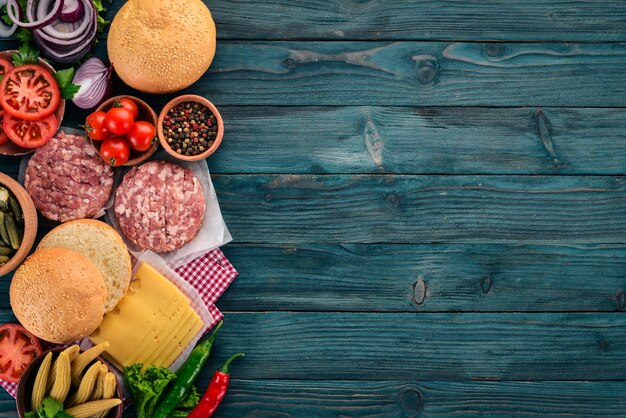 Zubereitung von Burger Fleisch Tomaten Zwiebeln Auf einem blauen Hintergrund aus Holz Draufsicht Freier Kopierraum