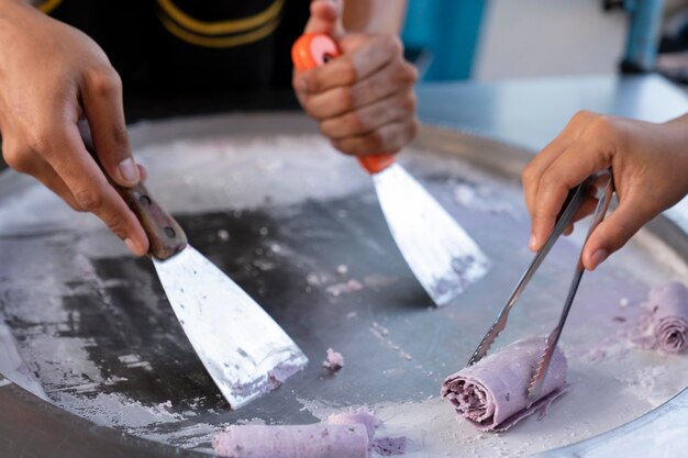 Zubereitung von eis, thailändisches street food. handspikes nehmen eine rolle eisbällchen.