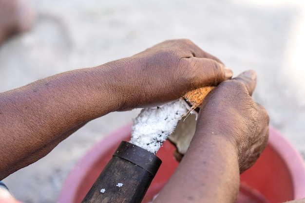 Zubereitung von Kokosflocken in einem speziellen Werkzeug für Kokosnüsse zu Hause in einem tropischen Innenhof auf der Insel Sansibar Tansania Afrika aus nächster Nähe