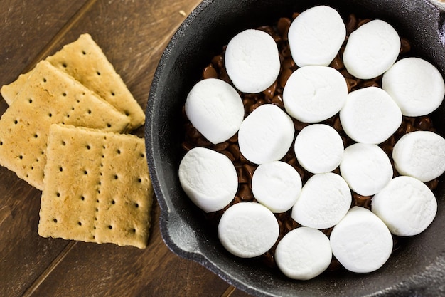 Zubereitung von Smores Dip mit großen Marshmallows in einer gusseisernen Pfanne zubereitet.