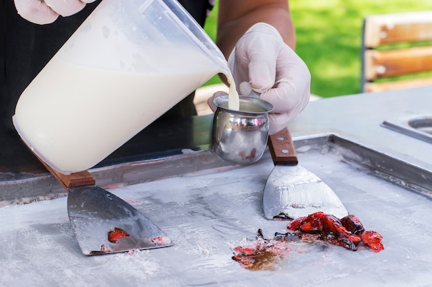 Zubereitung von Thai-Eis aus Naturcreme mit frischen Erdbeeren.