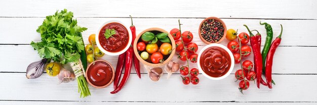 Zubereitung von Tomatensaucen und Gewürzen Kirschtomaten Gewürze Chilischoten Draufsicht auf weißem Holzhintergrund Freier Kopierraum