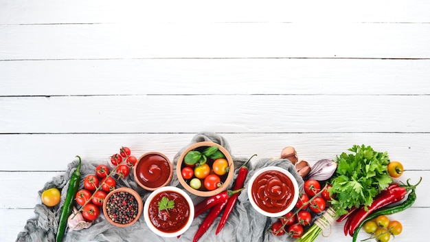 Zubereitung von Tomatensaucen und Gewürzen Kirschtomaten Gewürze Chilischoten Draufsicht auf weißem Holzhintergrund Freier Kopierraum