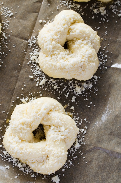 Zubereitungsprozess - rohe ungebackene Brötchen. Bereit, hausgemachte traditionelle Brötchen auf Backpapier zu backen.