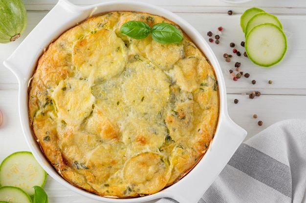 Foto zucchini-casserole in creme-käse-sauce in einer weißen backschüssel gesundes, komfortables vegetarisches essen