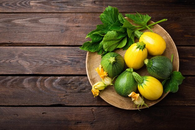 Foto zucchini mit blättern und blumen auf dunklem rustikalem holzhintergrund