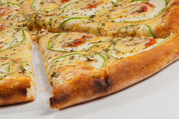 Zucchini-Pizza mit Knoblauch, garniert mit Auberginen und Tomatensauce auf weißem Hintergrund.