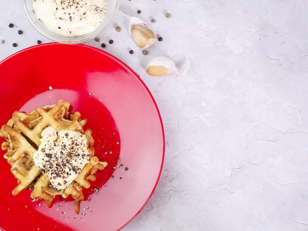 Zucchiniwaffeln auf einer roten Platte mit Soße und Gewürzen