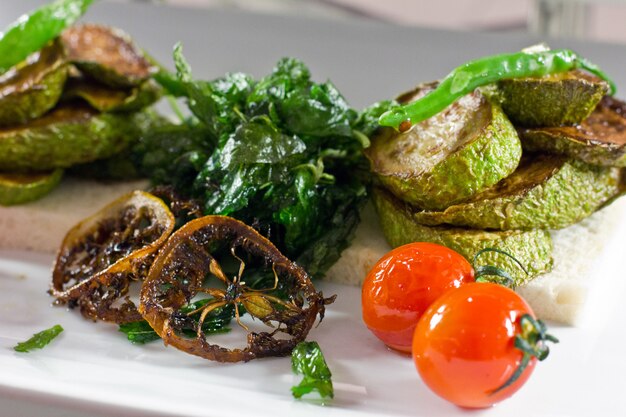 Zuccini assado com tomate cereja e pimenta verde em um branco