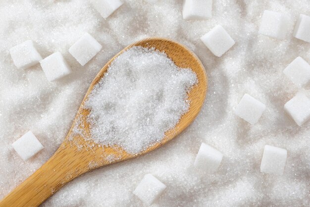 Zucker in einem Holzlöffel auf weißem Zuckerhintergrund