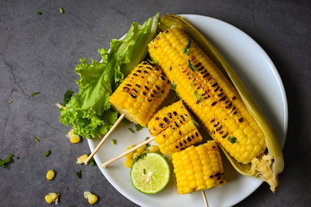 Zuckermais gekocht auf weißem Teller Zuckermais mit Salat, Gemüse, Limette, Koriander und Salat, reife Maiskolben, gegrillter Zuckermais für veganes Abendessen oder Snack