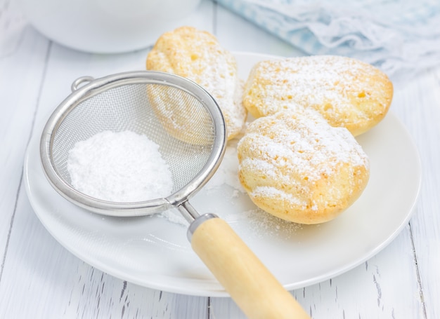 Foto zuckerpulver madeleines auf einem weißen tisch