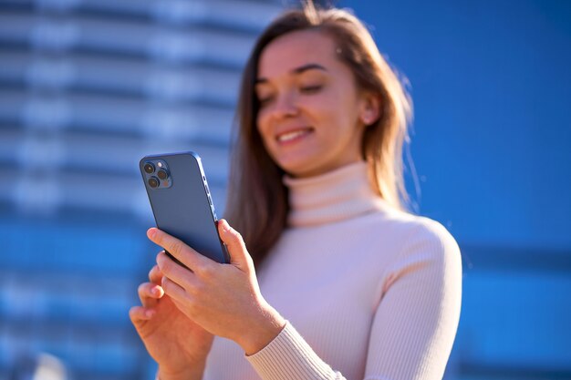 Zufällige moderne Frau, die Telefon im Freien verwendet