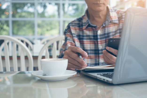 Zufälliger Geschäftsmann, der an Laptop-Computer im Kaffeehaus arbeitet